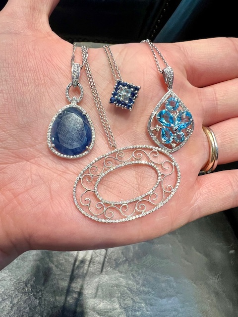 Four white gold necklaces with shades of blue and white.